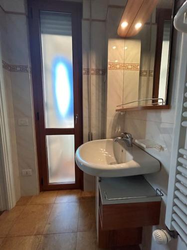 ein Badezimmer mit einem Waschbecken, einem Spiegel und einer Tür in der Unterkunft Residenza Versilia in Viareggio