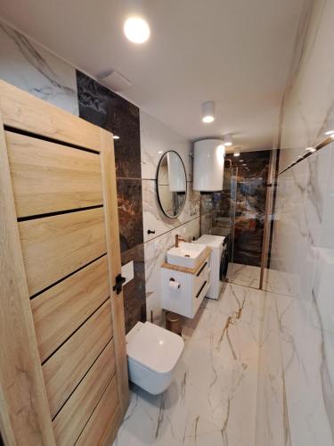 a bathroom with a toilet and a sink and a mirror at Apartament Kluskowe Widoki in Kluszkowce