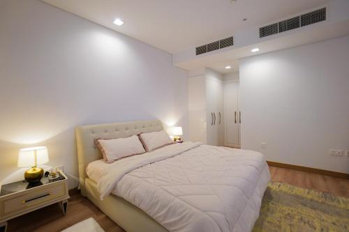 a white bedroom with a large bed and a table at Luxury Apartment by the Sea with Amazing Amenities at Pearl Qatar in Doha