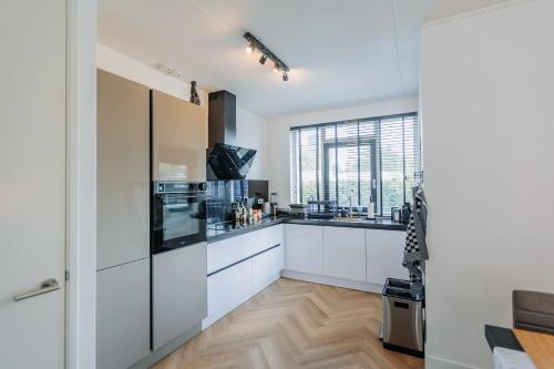 a kitchen with white cabinets and a large window at Dutch Design Villa with 6 luxurious bedrooms in Amsterdam