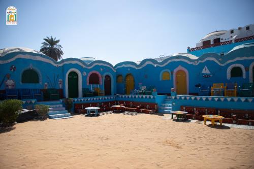 a blue building with tables and benches in the sand at Kato Waidi Nubian Resort in Aswan