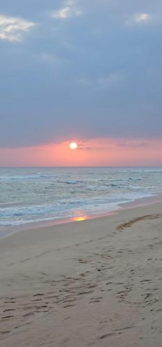 a sunset on a beach with the ocean at White Surfing Beach Resort in Unawatuna