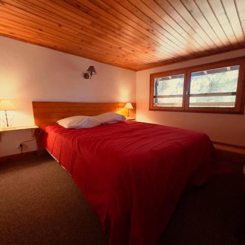 a bedroom with a red bed with a wooden ceiling at LE NID ROUDELA in Garin