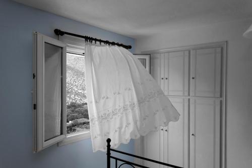 a window with a white curtain in a room at Theodora in Panormos