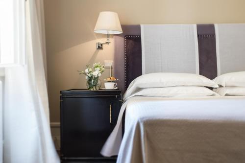 a bedroom with a bed and a table with a lamp at Hotel Francia E Quirinale in Montecatini Terme