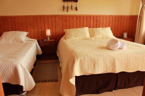 a bedroom with two beds and a bottle on the bed at Del Bosque Pucón - Hostal in Pucón