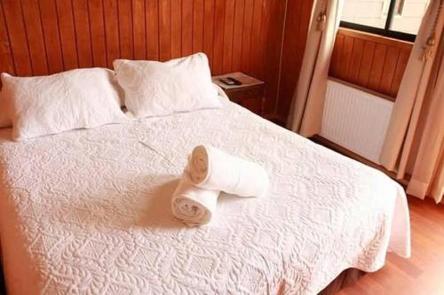 a white bed with two rolled towels on it at Del Bosque Pucón - Hostal in Pucón