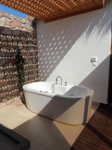 a bath tub in a bathroom with a stone wall at Ananda Beach Camp in Nuweiba