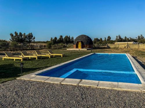 a swimming pool with two picnic tables and a barn at Domo ruta del vino Colchagua in Peralillo