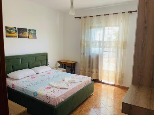 een slaapkamer met een groen bed en een raam bij Baka Guest House in Durrës