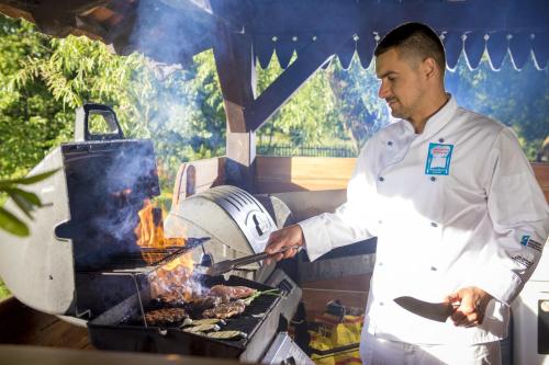 a man is cooking food on a grill at Pałac Galiny in Bartoszyce- Galiny