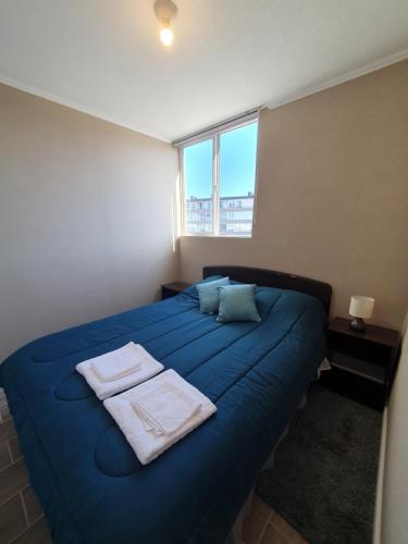 a bedroom with a blue bed with towels on it at Acogedora habitación en departamento nuevo in Puerto Montt