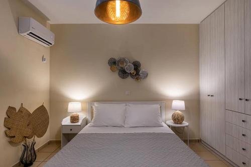 PosidhoníaにあるStelios-Korina Villa with Pool and Stunning View in Syros Posidoniaの大きなベッドと2つのランプがある寝室
