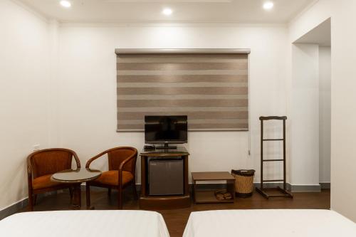 a room with two chairs a table and a television at Lantern Hotel in Ho Chi Minh City