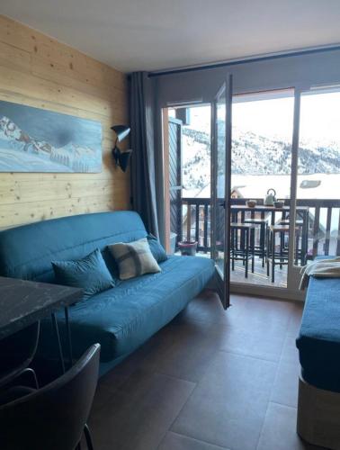 un salon avec un canapé bleu et un balcon dans l'établissement appartement le Chamois 312 Valmeinier 1900 piscine extérieur uniquement ouverte saison d été avec 1 chambre, à Valmeinier