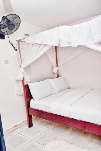 a bed with a canopy in a room with a fan at Magnolia Apartments in Kisumu