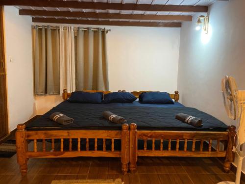 um quarto com uma cama de madeira e almofadas azuis em Coorg klusters estate stay em Virajpet