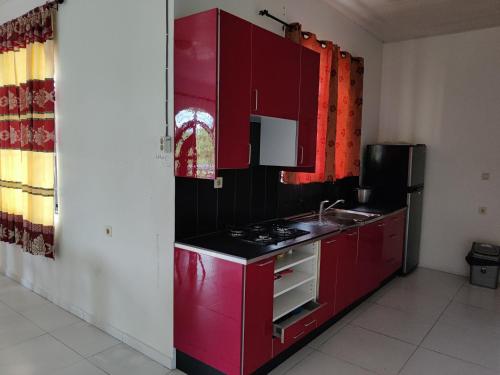 a red kitchen with a stove and a sink at Minia House in Flora