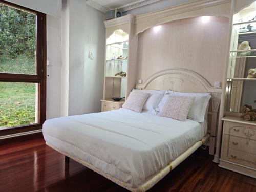1 dormitorio con 1 cama con sábanas blancas y ventana en APARTAMENTO VALDEARENAS, en Renedo de Piélagos