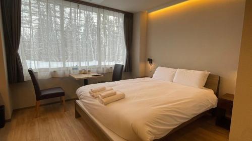 una camera con un letto bianco, una sedia e una finestra di WHITE HOTEL GRAND HAKUBA a Ōmachi