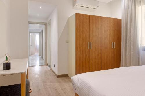 カイロにあるVESTA - New Cairo Residenceのベッドルーム1室(ベッド1台付)、木製キャビネットが備わります。