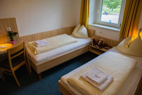 a room with two beds and a table and a window at Landhotel Haagerhof in Aigen im Mühlkreis