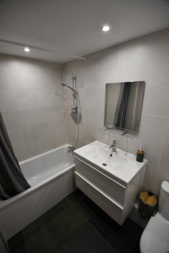 une salle de bain avec une baignoire blanche, un lavabo et un miroir dans l'établissement Cocon & Cosy Annecy, à Annecy