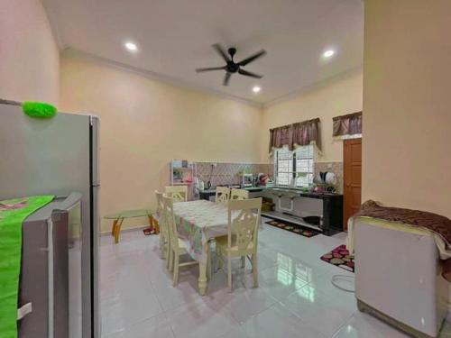 a kitchen with a table and chairs and a ceiling fan at Airport Kelantan HOMESTAY & TRANSIT ROOM in Kota Bharu