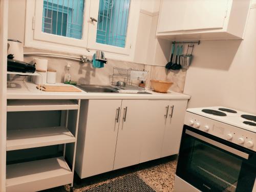 una cucina con armadi bianchi, lavandino e piano cottura di Selini's apartment ad Atene