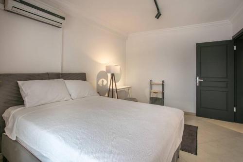 1 dormitorio con cama blanca y puerta negra en flaneur home en Marmaris