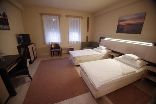 a hotel room with two beds and a desk at Hotel Vadászkürt Superior in Székesfehérvár