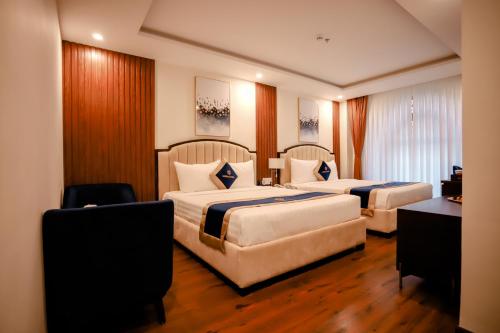 a hotel room with two beds and a desk at Sandals Vista Hotel in Bao Loc