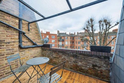 a balcony with a table and chairs on a brick wall at Chelsea Superior Apartment - 10 Minutes from Stadium in London