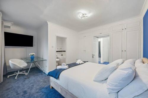 a white bedroom with a large bed and a desk at Chelsea Superior Apartment - 10 Minutes from Stadium in London
