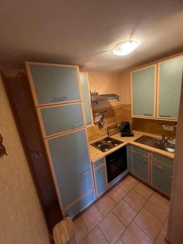 una pequeña cocina con armarios azules y fregadero en 30qm Wohnung in Hainburg en Hainburg