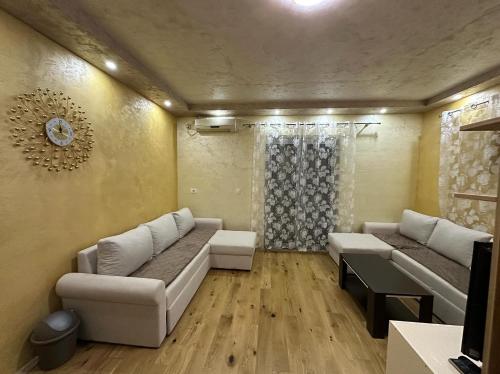 een woonkamer met twee banken en een klok aan de muur bij Lux Apartment Oasis in Rafailovici
