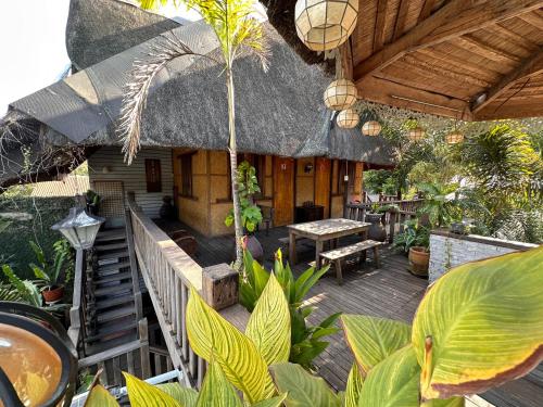 a patio with a thatched house with a table and benches at Mount Pinatubo Base Camp at CASA HERMOGINA in Santa Juliana