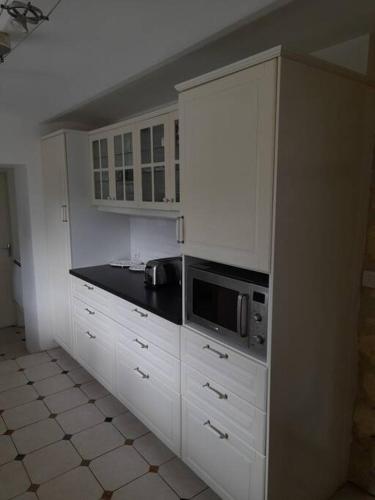 a kitchen with white cabinets and a microwave at Belle maison du 18e siècle in Bazemont