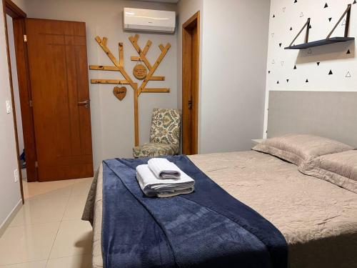 ein Schlafzimmer mit einem Bett mit einer blauen Decke und einem Stuhl in der Unterkunft Triplex independente in Cabo Frio