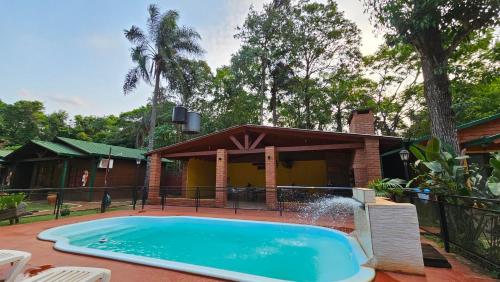 a swimming pool in front of a house at Cabañas Rincon Santa Maria in Puerto Iguazú