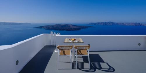 a table and two chairs on the balcony of a yacht at Kamares Apartments in Fira