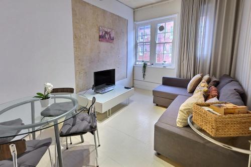 a living room with a couch and a glass table at 1 bedroom flat near Russel Square in London