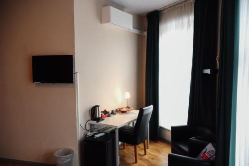a room with a table with chairs and a television at Hotel Brasserie de Kroon in Gulpen