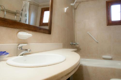 a bathroom with a sink and a mirror and a tub at Aldeas de Vacaciones - Feriendorf in Villa General Belgrano