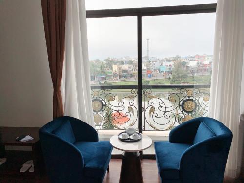 two chairs and a table in front of a large window at Sandals Vista Hotel in Bao Loc