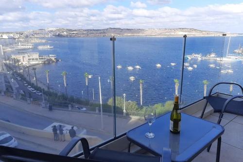 una mesa con copa de vino y vistas al agua en New Seafront apartment – Spectacular views en St. Paul's Bay