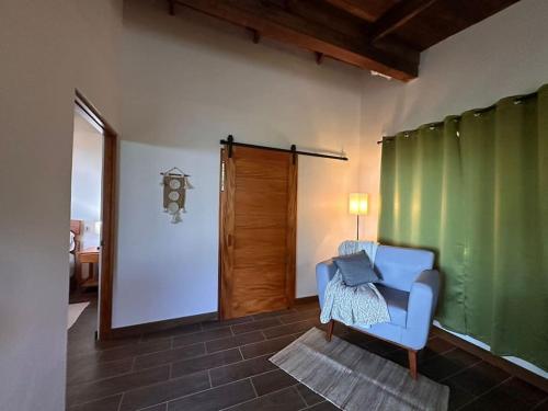 a living room with a blue chair and a green wall at Cabañas Areno Lodge. in Bijagua