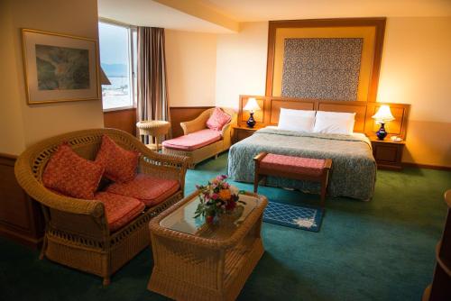 パヤオにあるPhayao Gateway Hotelのベッドと椅子が備わるホテルルームです。