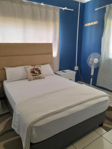 a bedroom with a large bed with a blue wall at Master Palace Guest House - Randfontien in Randfontein