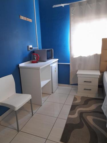 a kitchen with a table and a microwave in a room at Master Palace Guest House - Randfontien in Randfontein